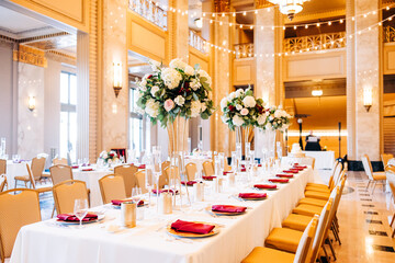 A beautiful art deco ballroom with string lights and set up for a wedding reception. A long table...