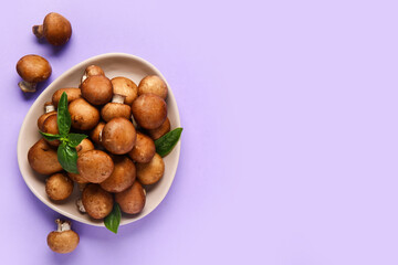 Plate with fresh mushrooms and basil on lilac background