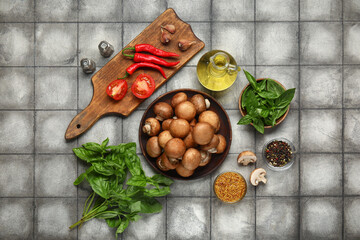 Plate with fresh mushrooms and different spices on grey tile background