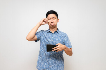 Asian man blue shirt holding wallet feels sad and cry about less money isolated