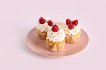 Plate with tasty raspberry cupcakes on grey background