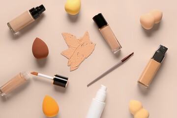 Bottles of makeup foundation with samples and sponges on beige background - obrazy, fototapety, plakaty
