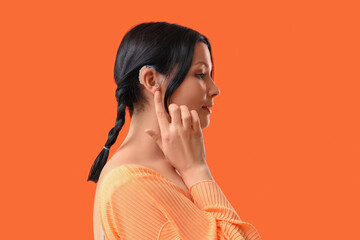 Young woman with hearing aid on red background, closeup - obrazy, fototapety, plakaty