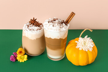 Glasses of tasty pumpkin latte with cinnamon and star anise on colorful background