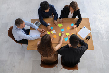 Group of business people working with pin board at table in office, top view