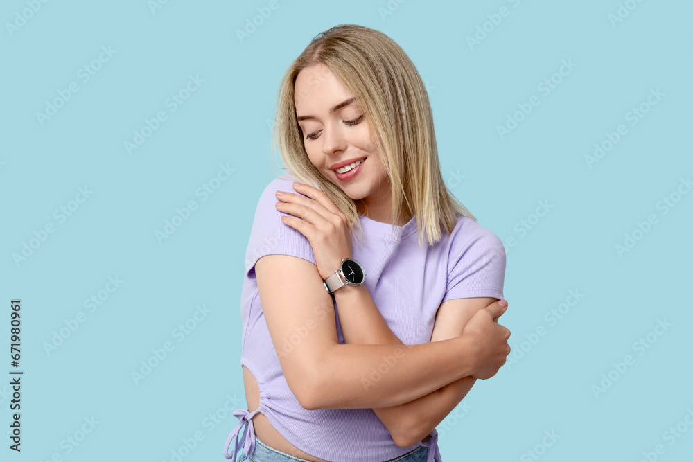 Canvas Prints Young woman hugging herself on blue background