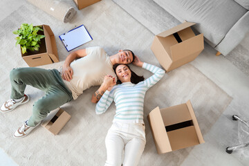 Happy young couple holding hands in room on moving day, top view
