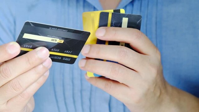 Man holding several credit cards and he is choosing a credit card to pay and spend Payment for goods via credit card. Finance and banking concept.