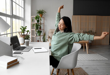 Young Asian woman stretching after work at home office