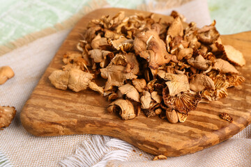 Wooden board with tasty dried mushrooms on table, closeup