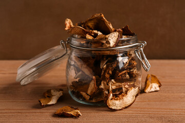 Jar with tasty dried mushrooms on wooden table