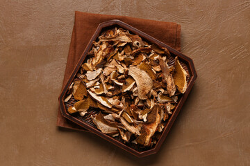 Tray with tasty dried mushrooms on brown background