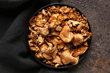 Plate with tasty dried mushrooms on dark background