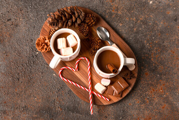 Cups of hot chocolate with marshmallows and cinnamon on dark background