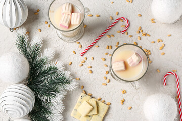 Glass cups of hot chocolate with marshmallows and candy canes on white background