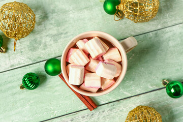 Fototapeta na wymiar Cup of hot chocolate with marshmallows and Christmas balls on green wooden background