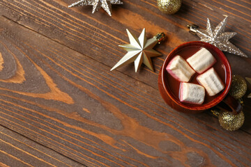 Cup of hot chocolate with marshmallows and Christmas balls on wooden background
