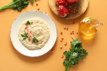 Plate of tasty baba ghanoush with oil and pomegranate on orange background