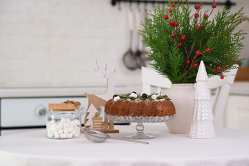 Christmas home interior in white kitchen-Christmas chocolate bundt cake with fresh berries and rosemary. Winter baking at Christmas. Ceramic vase with spruces brunches..