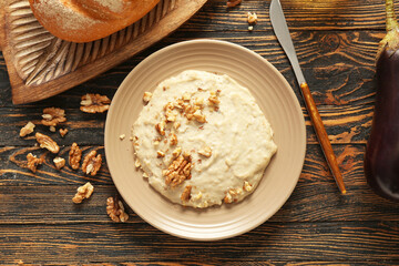 Plate of tasty baba ghanoush on wooden background