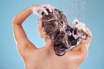 Woman, back and shampoo, haircare in shower and hygiene with water drops on blue background. Grooming, cosmetic care and sustainability, female person and morning routine, soap or foam in hair