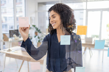 Planning, thinking and writing by black woman in office for agenda, calendar or schedule on sticky note. Creative, strategy and lady in idea for future, vision and innovation, mission and career goal
