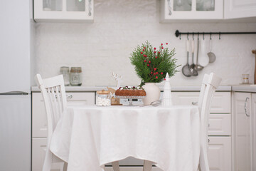 Christmas home interior in white kitchen-Christmas chocolate bundt cake with fresh berries and rosemary. Winter baking at Christmas. Ceramic vase with spruces brunches..