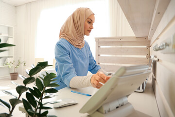 Muslim medical intern working at reception in clinic