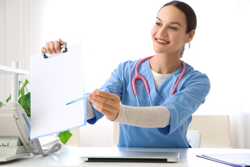 Female medical intern with clipboard at table in clinic