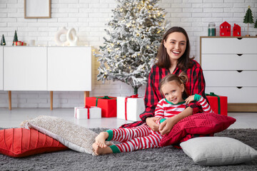 Happy mother and her little daughter at home on Christmas eve - obrazy, fototapety, plakaty