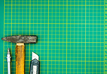 screwdriver hammer and knife isolated on green cutting mat