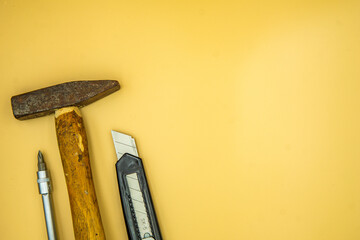 screwdriver hammer and knife isolated on cream background