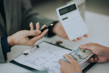 Close-up photo of a real estate agent offering a contract to purchase or rent a residence. Businessman holds small house model with property insurance at table in home sales office