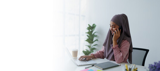 Muslim female employee Using the phone to talk to customers in the office.