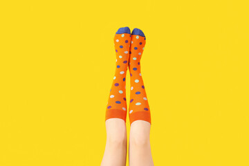 Legs of young woman in socks on yellow background - obrazy, fototapety, plakaty