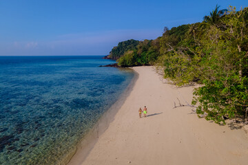 a couple of men and women sitting at the beach of Koh Kradan island in Thailand
