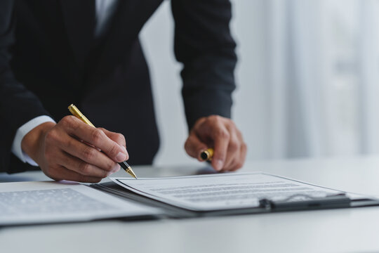 Businessman holding a pen to sign a contract, making a detailed agreement, business contract for finance, real estate, insurance, taxes and signing an official document.