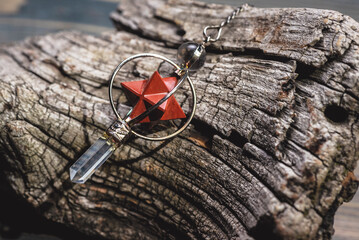 Magic pendulum on the wooden stump close up background.