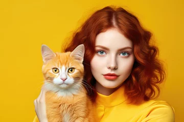 Foto op Plexiglas Portrait of a beautiful red-haired young woman and cute orange cat isolated on yellow background © Veniamin Kraskov