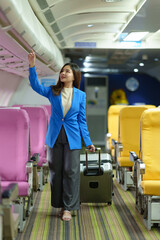 Businesswoman, confident tourist walks with suitcase, checks seat, flight number, puts her suitcase on shelf inside airplane travel lifestyle concept.