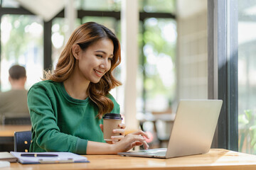 Pleasant happy young woman doing independent work using home computer Attractive woman studying online using laptop software Internet browsing information - obrazy, fototapety, plakaty