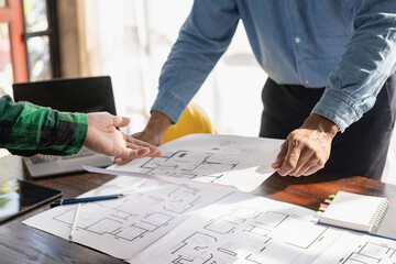 Engineer and businessman discussing construction project in office, team of engineers reviewing construction blueprints on new project with engineering tools at table in office