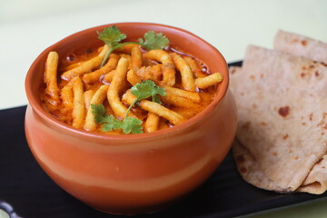 Shev bhaji or sev bhaji, a unique curry recipe made with the combination of spicy gathiya or fried besan noodles and curry from khandeshi kala masala, Can be served with both chapatis or Bhakris