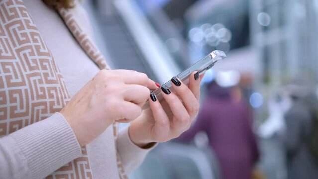 Close-up. People in international airport. Female traveler look at phone, search for boarding pass or flight cancelation information. 4K