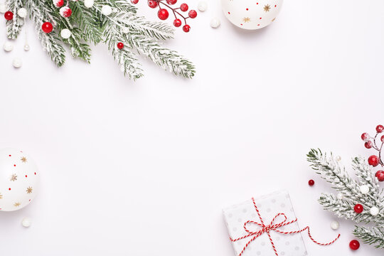 Christmas greeting card. Frame of Christmas decorations, gift and fir-tree. White background as copy space. Elegant classic style.