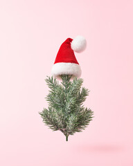 Christmas tree in Santa hat on pink background. Christmas greeting card, concept, minimal style.