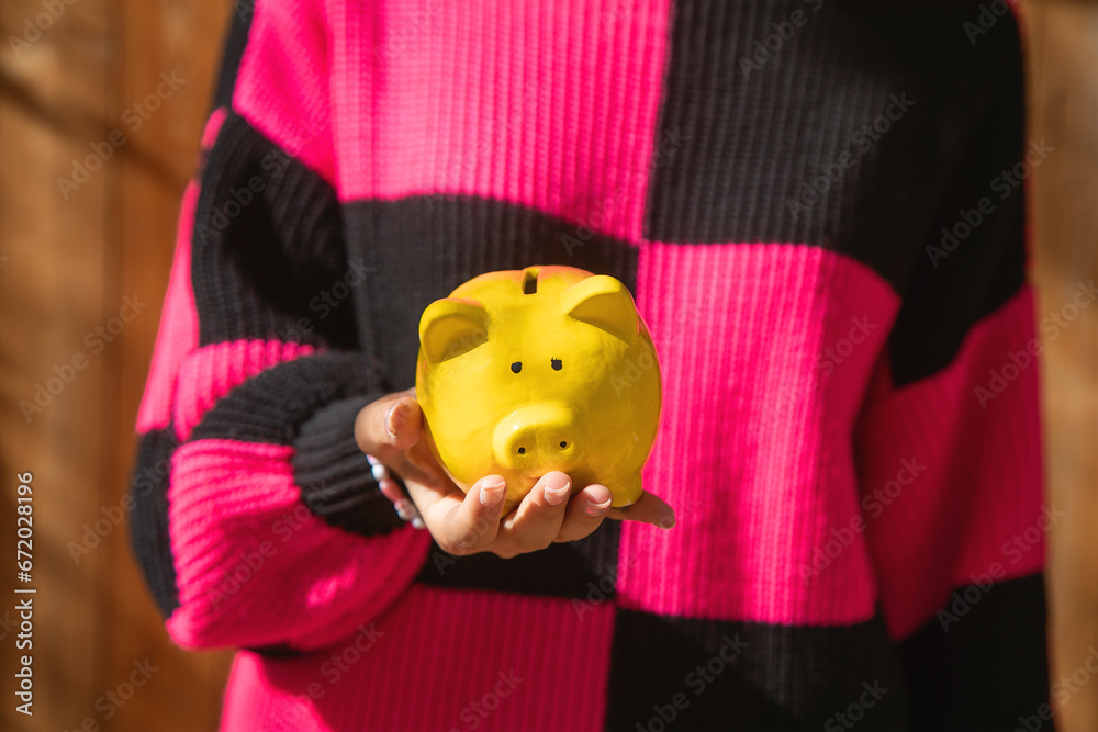 Poster caucasian young woman holding a piggy bank.