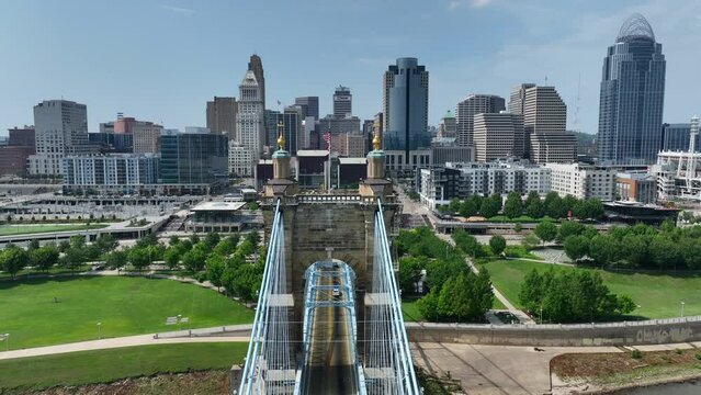 Cincinnati skyline with iconic Roebling Suspension Bridge foreground, skyscrapers, and riverfront park. Aerial reveal of skyline on summer day.