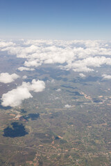 Fototapeta premium Beautiful view from the airplane window from above to the clouds, mountains, roads, rivers. Picturesque landscape from a helicopter window on a sunny day.