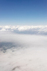 Beautiful view from the airplane window from above to the clouds, mountains, roads, rivers. Picturesque landscape from a helicopter window on a sunny day.